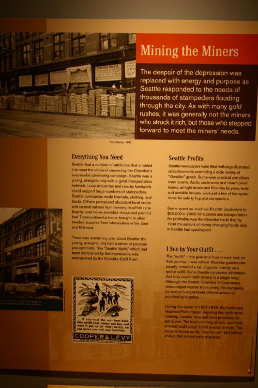 2007-09-03 10:22:42 ** Seattle ** Abbau der Minenarbeiter

Die Hoffnungslosigkeit der Depression wurde durch Kraft und Zielstrebigkeit abgelöst, als Seattle auf den Bedarf tausender Goldsucher reagierte, die die Stadt überfluteten. Wie bei vielen Goldräuschen waren es oft nicht die Goldsucher, die viel Geld verdienten, sondern die, die den Bedarf der Goldsucher bedienten.

Alles Was Man Braucht

Seattle hatte einige Eigenschaften, die es ihr ermöglichten, den Bedarf zu decken, der durch die erfolgreiche Werbekampagne der Handelskammer entstand. Seattle war eine junge, energiereiche Stadt mit einem guten Transportnetzwerk. Lokale Industrien und nahe Landwirtschaft konnten große Mengen Goldsucher unterhalten. Firmen in Seattle stellten Decken, Kleidung und Stiefel her. Andere verarbeiteten die reichlich vorhandenen Ernten und konservierten Lachse, die in der Umgebung wimmelten. Kohleminen in der Nähe sorgten für viel günstigen Treibstoff. Transkontinentale Eisenbahnen brachten andere benötigte Waren aus dem Osten und Mittlerem Westen.

Es gab noch etwas anderes in Seattle: Die junge, energetische Stadt hatte Zweckbestimmung und Optimismus. Die 'Seele von Seattle', die durch die Depression geschwächt wurde, erwachte mit dem Klondike Goldrausch.

Seattle Profitiert

Zeitungen in Seattle waren voll von großen illustrierten Anzeigen, die eine Vielzahl von 'Klondike'-Gütern anpriesen. Einige waren praktisch und andere waren Betrug. Arktische Unterwäsche und insektenbeständige Masken, luftdichte Kocher und Klondike-Fahrräder, Zelte und tragbare Häuser waren nur einige der unzähligen Artikel, die den Goldsuchern zum Verkauf angeboten wurden.

Einige gaben bis zu $1.000 ($22.000 in 2005) für Vorräte und Beförderung aus. Der Klondike-Handel war so erfolgreich, daß sich in Seattle bis 1900 die Menge an Geld in täglichem Umlauf vervierfacht hatte.

An Deiner Ausrüstung erkenne ich ...

Die 'Ausrüstung' - die Geräte und Essen, die die Goldsucher auf ihrer Reise mitnahmen, war entscheident. Klondike-Ratgeber beinhalteten üblicherweise eine Liste von Gütern, die zu einer üblichen Ausrüstung gehörten. Einige Firmen in Seattle warben mit einer kompletten Ausrüstung für die Goldsucher bei nur einem Besuch eines Geschäfts. Obwohl die Handelskammer von Seattle Frauen von der Goldsuche abriet, gab ihre Frauenabteilung Auskunft über den Vorratseinkauf.

Im Winter von 1897-1898 begann die Berittene Polizei genügend Vorräte für ein Jahr für jeden der Minenarbeiter vorauszusetzen, der Kanada betrat. Essen, Kleidung, Unterkunft und Werkzeuge konnten 2.000 Pfund oder mehr wiegen. Dies wurde als die 'Eine-Tonne-Regel' bekannt, die sicherstellte, daß die Minenarbeiter gut vorbereitet waren.