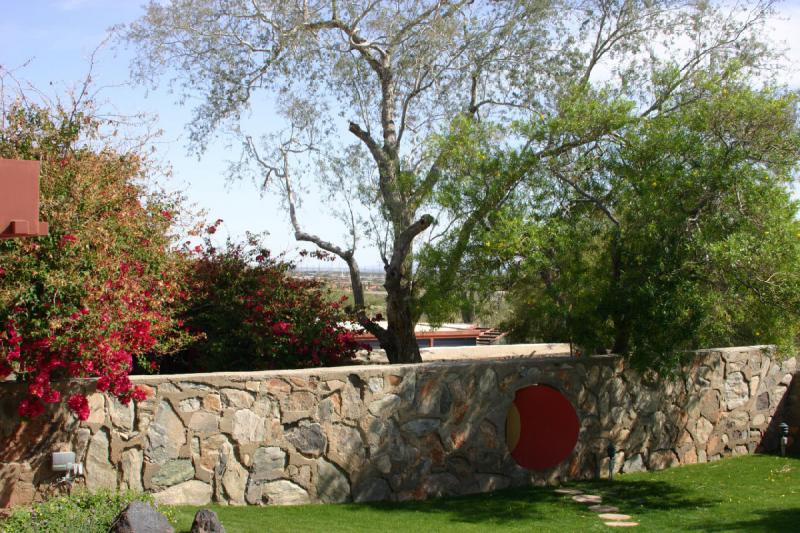 2007-04-14 15:07:10 ** Phoenix, Taliesin West ** Eine runde Holztür in der Gartenwand. Auch hier ist die Tür wieder rot.